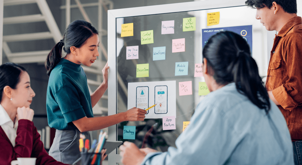 Team member leading a brainstorming session with sticky notes on a whiteboard