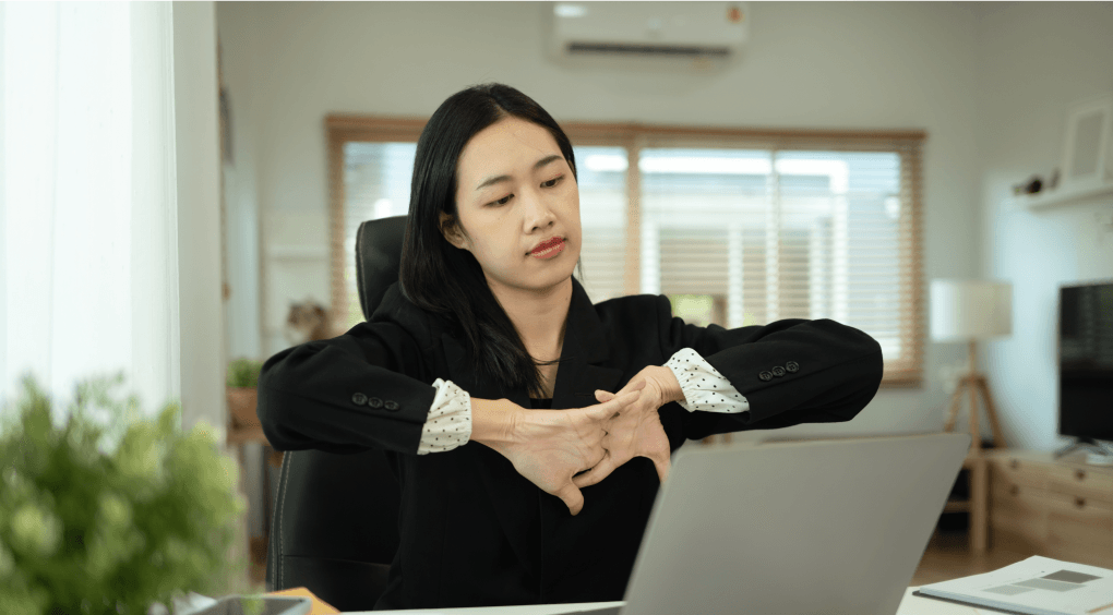 A professional stretching at her desk during a break from work