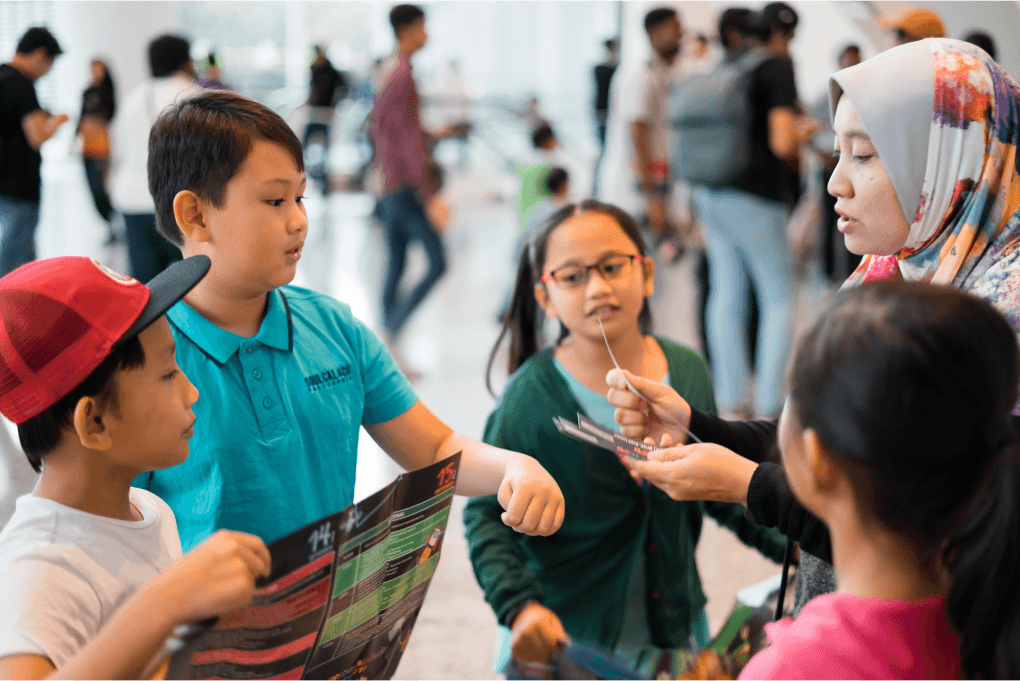 Teacher distributing materials to children during an interactive educational activity.